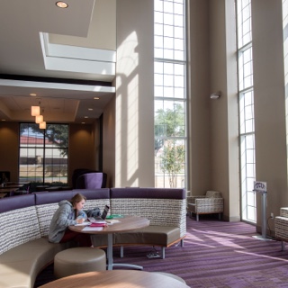 A girl studies in the sunlit lobby of the multi purpose building at TCU's Worth Hills