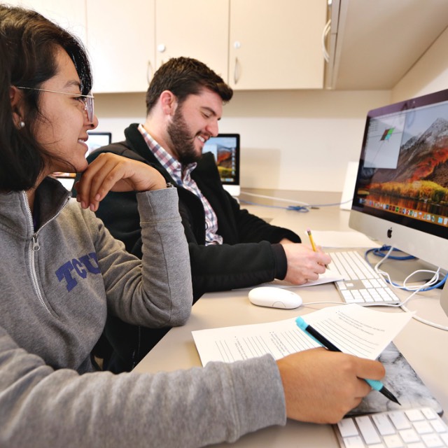 Students discuss details of a curriculum plan while working at computer workstations