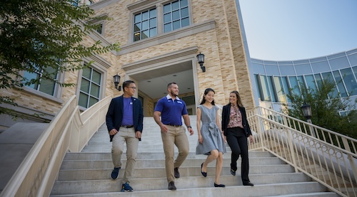 Four students walking down outdoor staircase